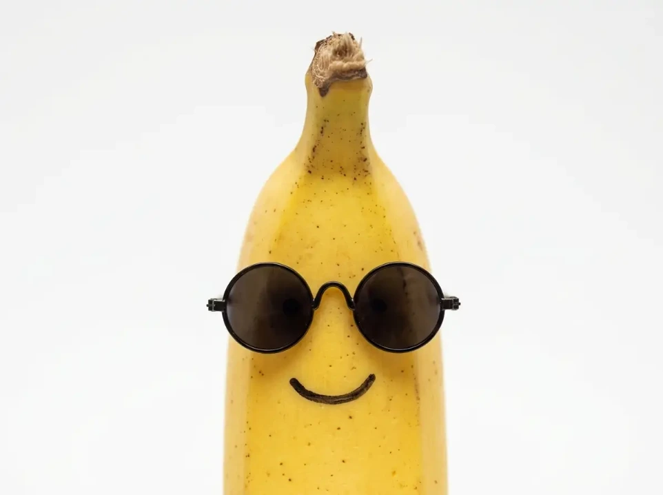 Banana sonriente con gafas de sol representando la frescura y simplicidad de una identidad visual profesional.